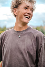 Person wearing a brown shirt with a blurred outdoor background