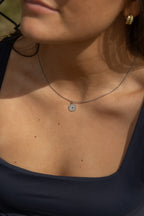 Close-up of a person wearing a silver necklace with a pendant that says god is good.