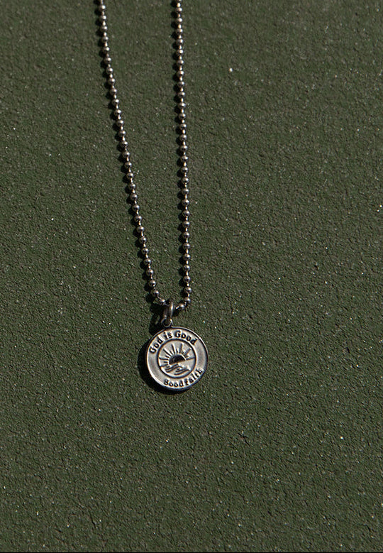 silver necklace that says god is good