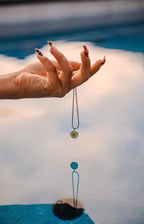 Hand holding a necklace over a blurred pool background